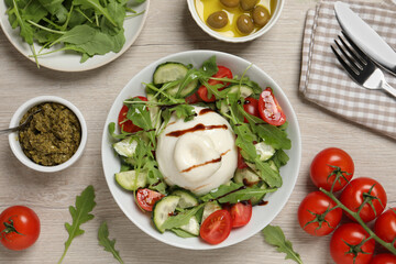 Delicious burrata salad served on wooden table, flat lay