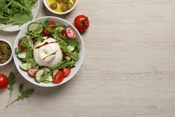 Delicious burrata salad served on wooden table, flat lay. Space for text