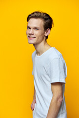 vertical portrait of a cute guy in a light t-shirt on a yellow background