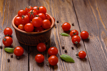 Brown bowl with cherry tomatoes and spices on dark wooden background, selective focus.