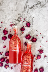 homebrew rose Kombucha in swing top glass bottle with dried rose buds on white table background., fermented tea drink, healthy beverage.
