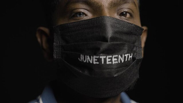 Close up shot of man with juneteenth medical face mask looking at camera during coronavirus covid pandemic - conept of freedom and liberty