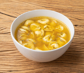 Cappelletti or tortellini brodo soup in a bowl over wooden table