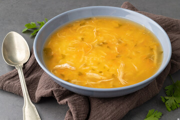 Chicken soup in a bowl over stone background
