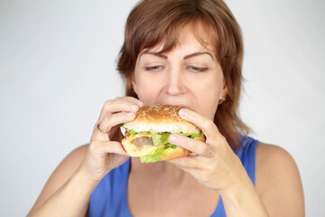 Portrait of young beautiful hungry woman eating burger. Diet concept.