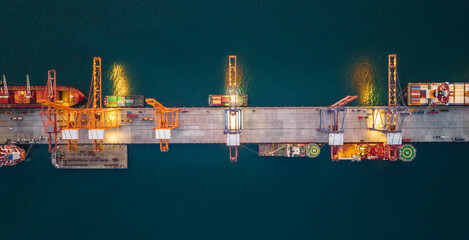 Obraz premium crane loading cargo container to container maritime ship in the international terminal container depot yard port concept freight shipping by ship at sunrise