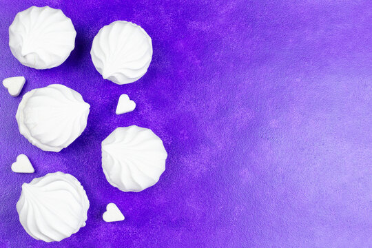 Airy white marshmallows and sugar in the form of a heart on a purple (lilac) background. Space for text. Recipe for cooking.