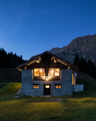 Night front view of newly refurbished chalet in the Swiss Alps and lights on