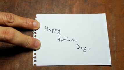 Hand written motivational word Happy fathers day. Men hand holding lifestyle motivational positive words written on a wooden background. Business, signs, symbols, concepts. Copy space.