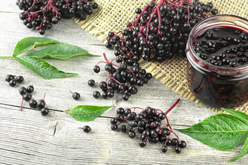 Fresh ripe black elderberries, elderberry syrup and leaves of elderberry on rustic wooden boards...
