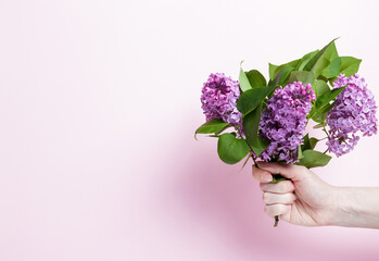 girl holding a bouquet of lilacs on a pink background