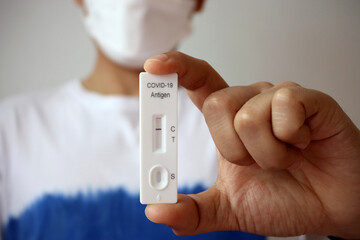 Man holding Rapid Antigen Test kit with Negative result during swab COVID-19 testing. Coronavirus...