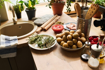 High angle view no people shot of potatoes, rosemary and thyme, cherry tomatoes and other products on kitchen counter