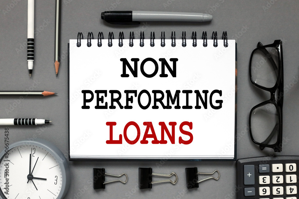 Poster non performing loans. text on an open notebook on a gray background near calculator glasses