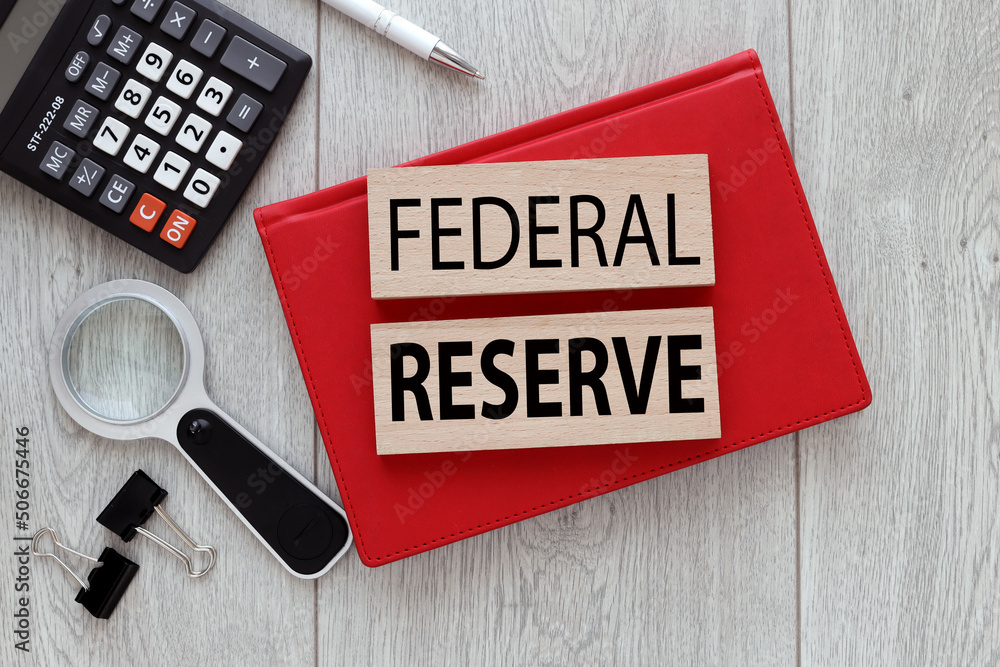 Aufkleber federal reserve text on wooden blocks on a notepad on a wooden background next to a calculator and v