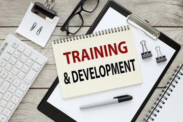 Training and Development. notepad with text on a wooden table and a folder with a clip. keyboard . working table