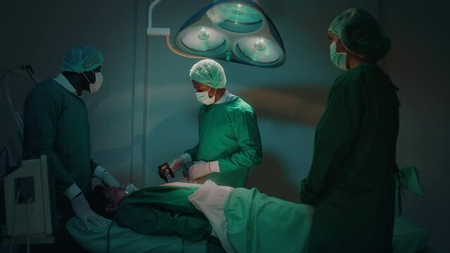 Professional doctors in the operating room making  CPR and use defibrillator electrical device to saving a patient life. health care concept.