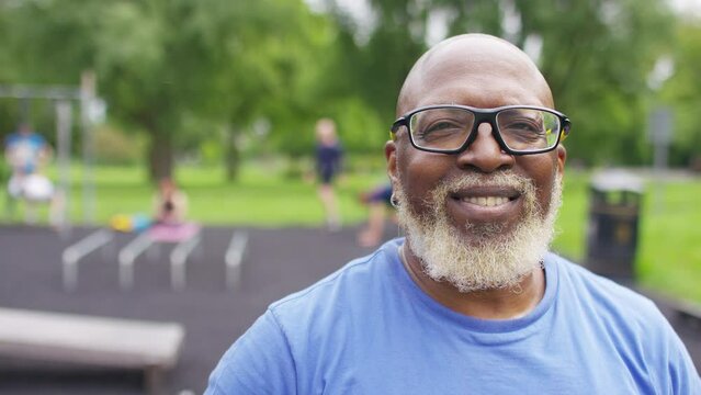 Portrait of attractive senior black man in a gym park smiling to camera, in slow motion