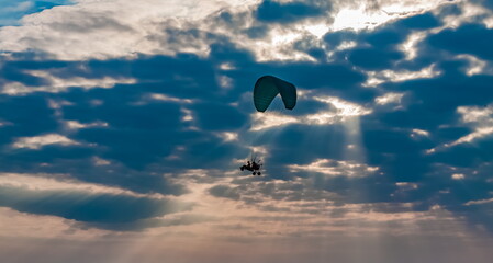 Fototapeta na wymiar Paraglider on the background of a sunset sky with clouds in summer