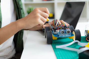An Asian boy is building a metal robot