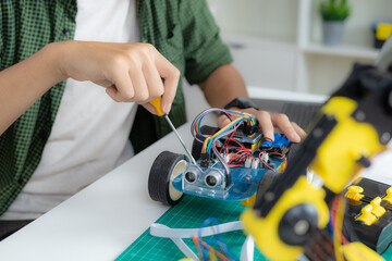 An Asian boy is building a metal robot