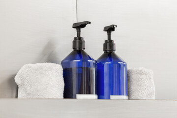 Two dispensers with soap and antiseptic with towels on a gray background in a beauty studio
