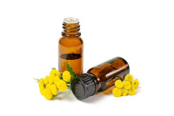 Essential oil of medicinal herb tansy in a dark glass bottle on a white isolated background. Aromatherapy, spa, skin care.