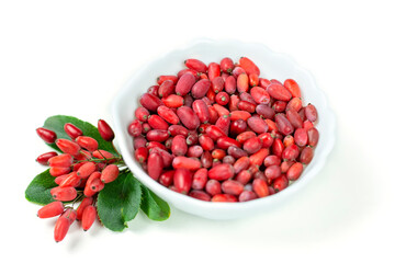 Fresh red barberry berries with green leaves in a white cup on a white isolated background.