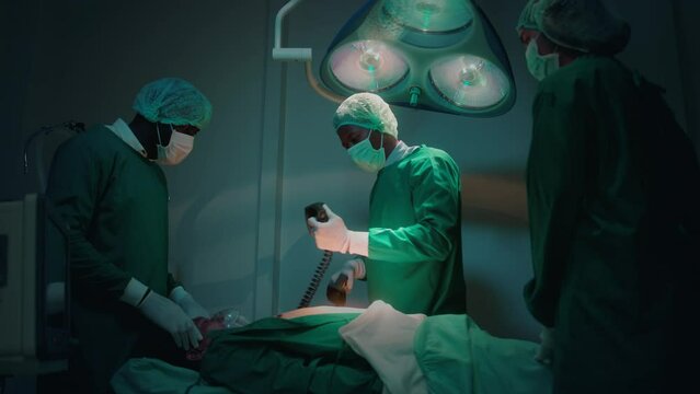 Professional doctors in the operating room making  CPR and use defibrillator electrical device to saving a patient life. health care concept.
