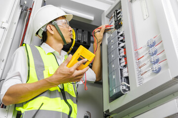 Electrical engineer or repairman holding digital multimeter to inspecting the electrical system in a factory.