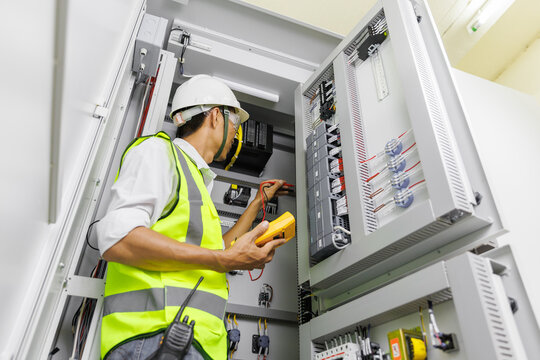 Electrical engineer or repairman holding digital multimeter to inspecting the electrical system in a factory.
