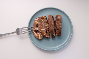 Homemade mosaic chocolate biscuit cake served in a blue plate, selective focus. It is called 