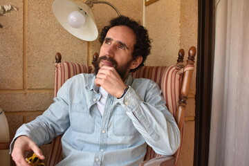 Joven pensativo sobre un futuro incierto sentado en una mecedora. Concepto nostálgico.