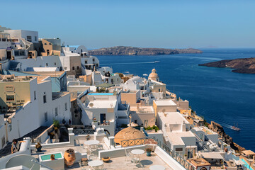 Top view of Fira city with white buildings of hotels, cafes, restaurants and the waters of the volcanic caldera on a sunny summer day. Santorini island, Cyclades, Greece