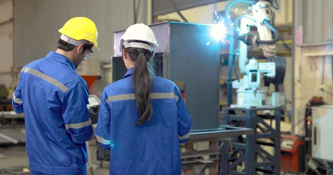 Male and female industrial engineers check and control welding robotics automatic arms machine in intelligent factory industrial with monitoring system software. - Powered by Adobe