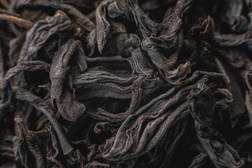 Black loose leaf tea as a background. Texture of dry black tea leaves. Dark background. Extreme macro mode. black leaf tea closeup
