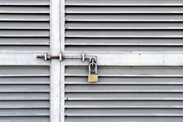 Small padlock hanging on closed metal doors