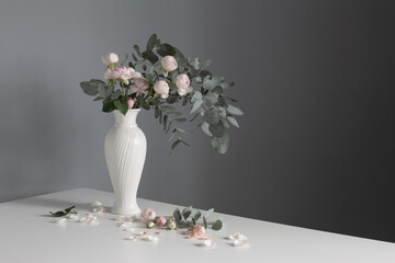 bouquet of pink roses in ceramic white vase  on background gray wall