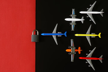 Set of toy planes next to a padlock on a black and red background. The concept of a no-fly zone, sanctions and an air embargo. Non-flying weather concept. copyspace.