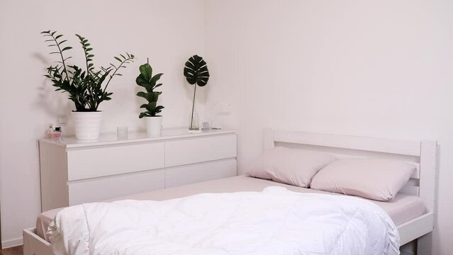 White blanket falls on the bed. Change of bed linen in the bedroom. Beautiful bright room in a modern style