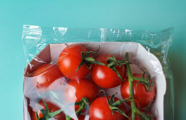 red tomatoes in transparent packaging on a green background