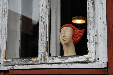 Kobieta z drewna w starym oknie. - obrazy, fototapety, plakaty