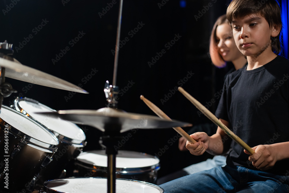 Wall mural Young woman teaching boy to play drums.