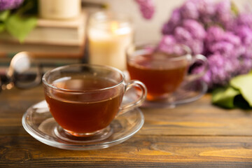 A cup of green tea against the background of a spring bouquet of lilacs . Romantic composition with books and candles. spring tea drink. Place to copy. Romantic concept.