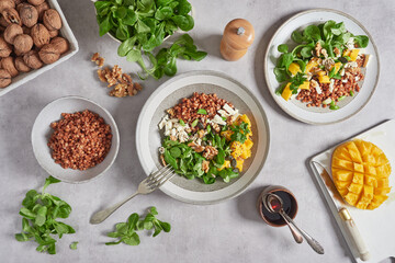 lamb's lettuce salad with mango, lentils and walnuts. Top view at the kitchen table with cutlery, dressing bowl and other ingredients.