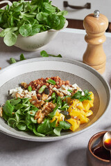 close-up view of a plate of lamb's lettuce salad with mango, walnuts, lentils and feta cheese with soy dressing