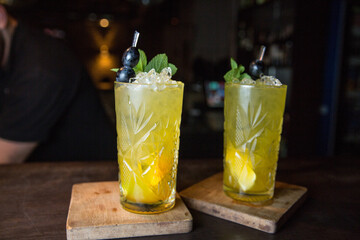 Glass of cocktail with ice. Mojito with ice on a wooden tabletop on a dark background.