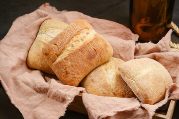 Italian ciabatta bread or bun in a wooden box with pink kitchen towel. Freshly baked traditional bread. Homemade rustic atisan bread or Italian Ciabatta. Shallow depth of field
