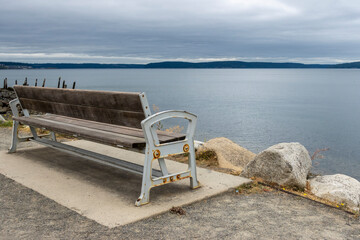 Angled view behind a wooden park bench with the Tacoma city skyline off in the horizon