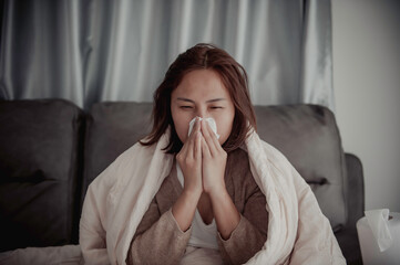 Asian sick woman sit on the sofa stay at home,The woman felt bad, wanted to lie down and rest,high fever